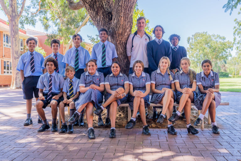 Guildford Grammar School Indigenous students sitting together for a photo on campus under a tree.
